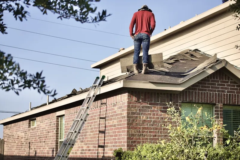 Professional roofer working on a residential roof in Massena